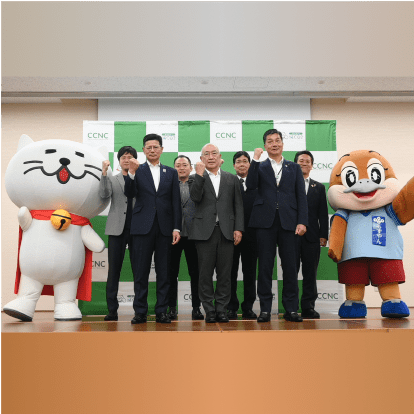 記者発表会で参加者と共にガッツポーズをする着ぐるみニャートラル