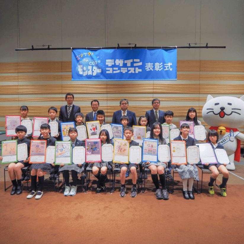 自身が描いたモンスターカードと賞状を持つ受賞者たちとニャートラルの記念写真